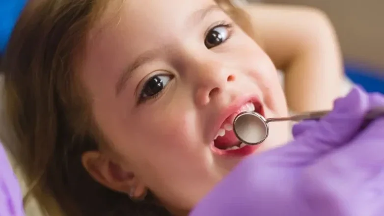 A child calmly having her teeth examined.